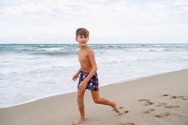 Бесплатное фото Мальчик в полный рост веселится на пляже