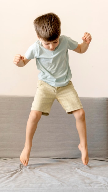 Full shot boy jumping on couch