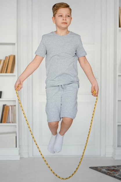 Full shot boy jumping rope indoors