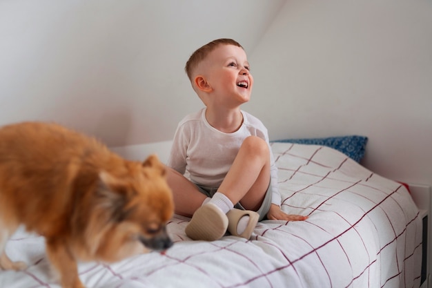 Бесплатное фото Мальчик в полный рост играет с собакой в помещении