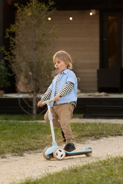 Foto gratuita ragazzo a tutto campo che gioca con lo scooter
