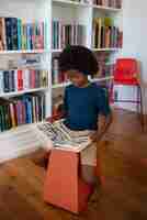 Free photo full shot boy reading comics at home