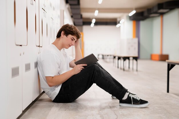 Full shot boy reading on floor at school