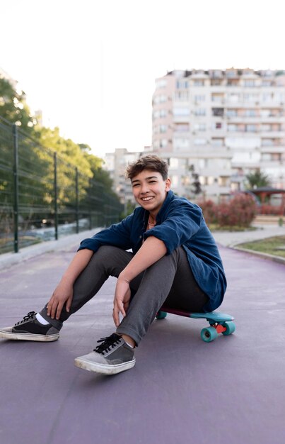 スケートボードに座っているフルショットの少年