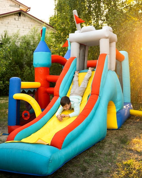 Full shot boy sliding on bounce house