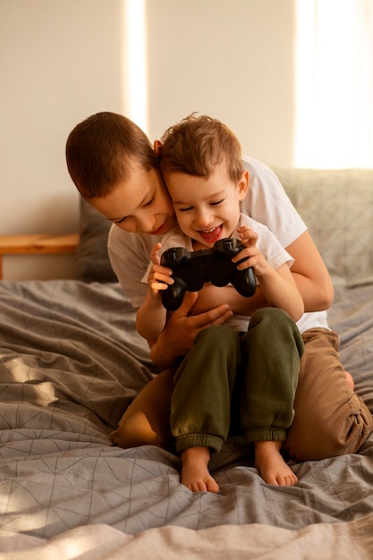 Free photo full shot brothers playing videogames