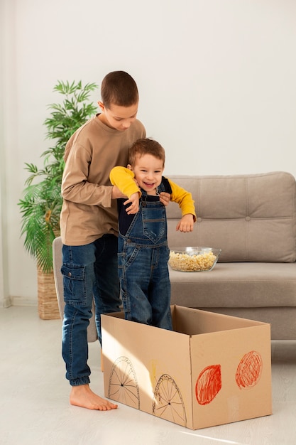 Free photo full shot brothers playing with box