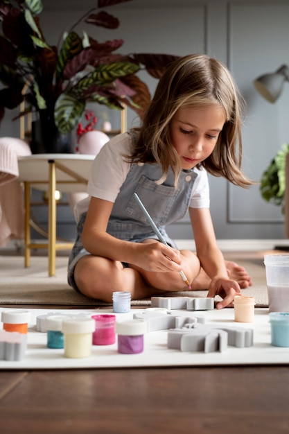 Full shot child on floor painting