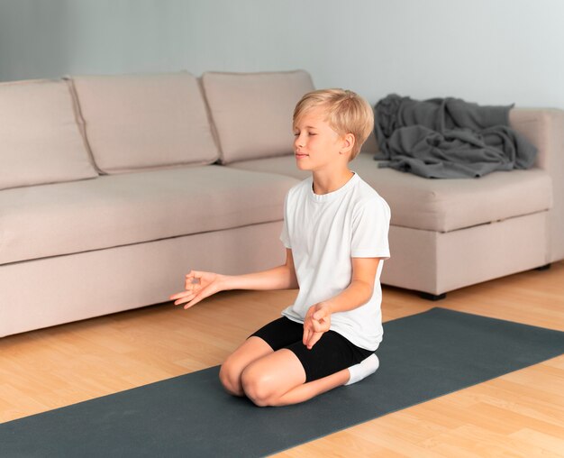Полный ребенок медитирует в помещении