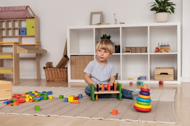 Полный снимок ребенка, играющего с красочными игрушками