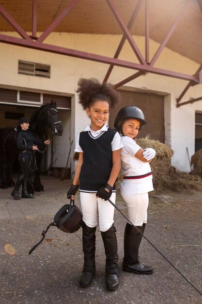 Полный снимок детей, которые учатся кататься на лошадях