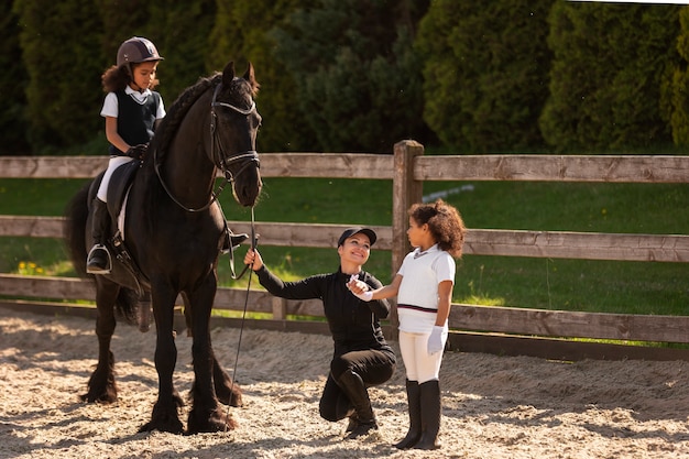 Foto gratuita bambini a figura intera che imparano a cavalcare