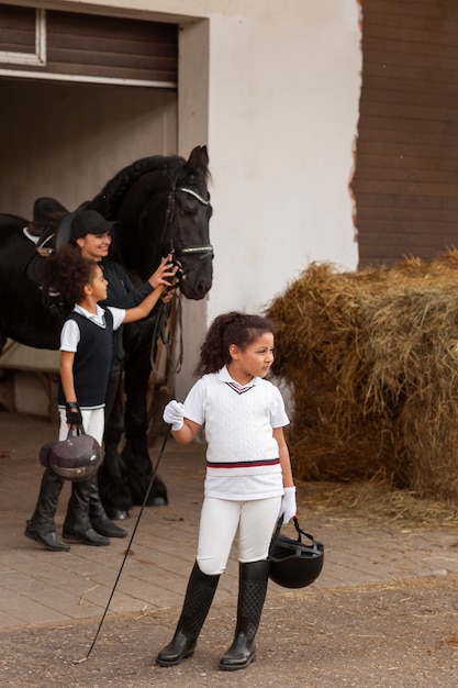 Foto gratuita bambini a figura intera che imparano a cavalcare