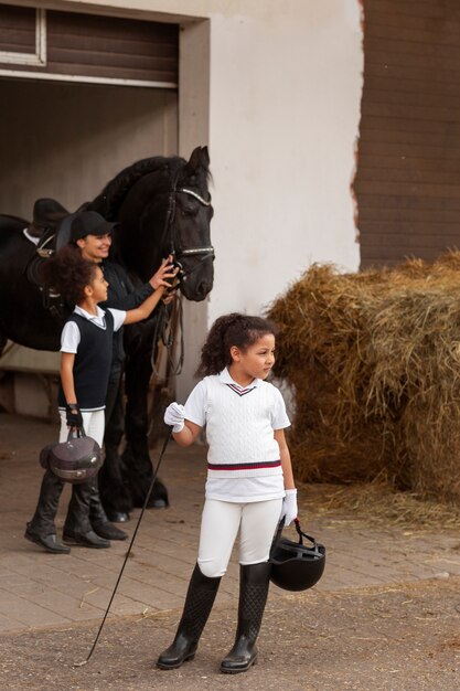 Full shot children learning to ride horses