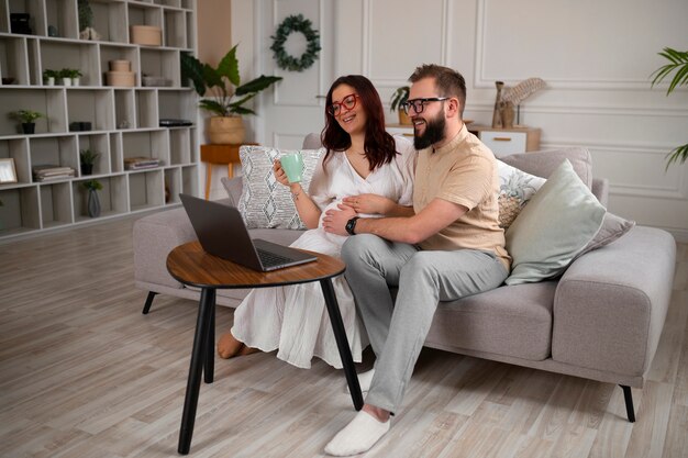 Full shot couple announcing pregnancy with laptop