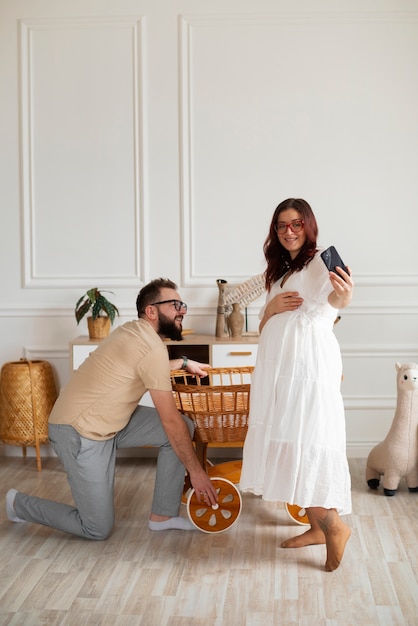 Full shot couple announcing pregnancy with smartphone