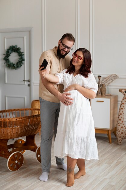 Full shot couple announcing pregnancy with smartphone