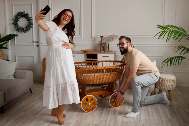 Full shot couple announcing pregnancy with smartphone