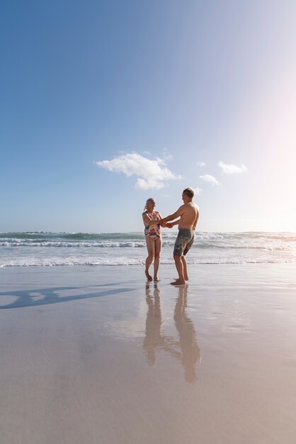 Full shot couple dancing on beach