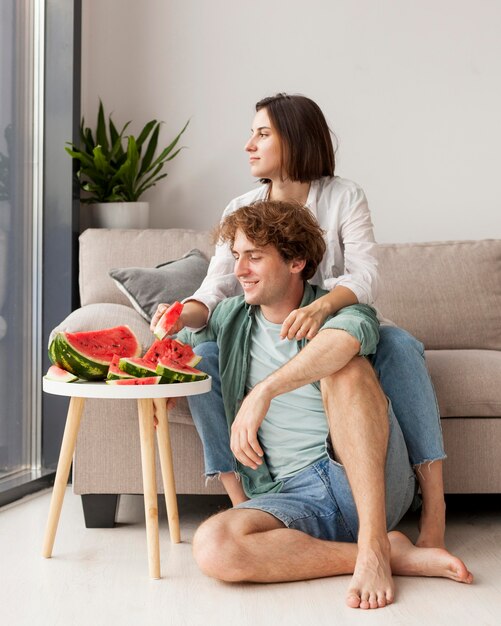 Full shot couple eating watermelon