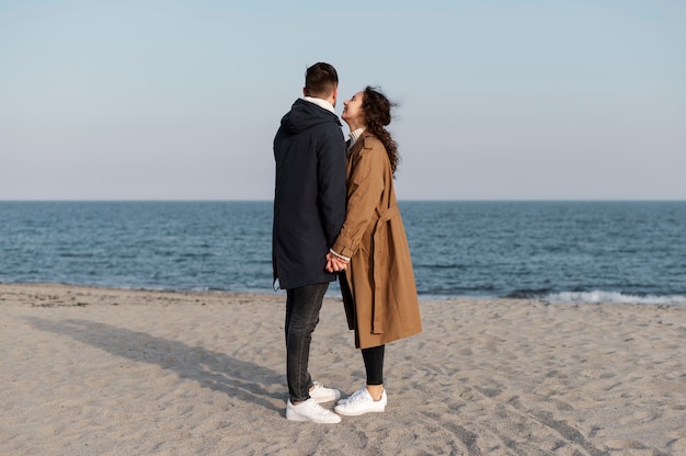 Full shot couple holding hands on beach