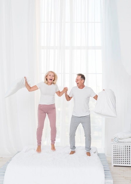 Free photo full shot couple jumping in the bed