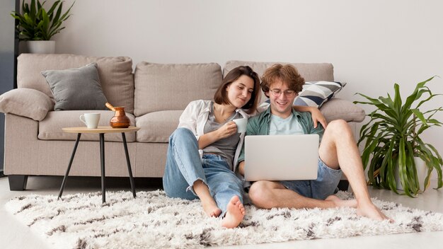 Full shot couple looking at laptop