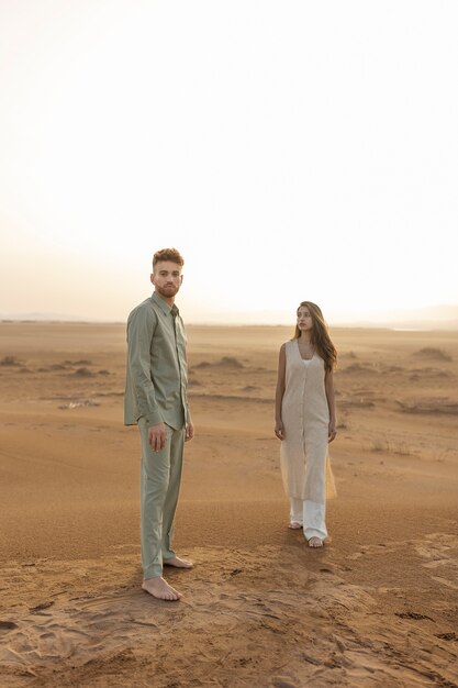 砂漠でポーズをとるフルショットカップル
