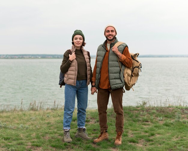 Full shot couple posing near water