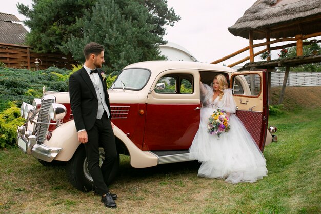 Full shot couple posing with vintage car