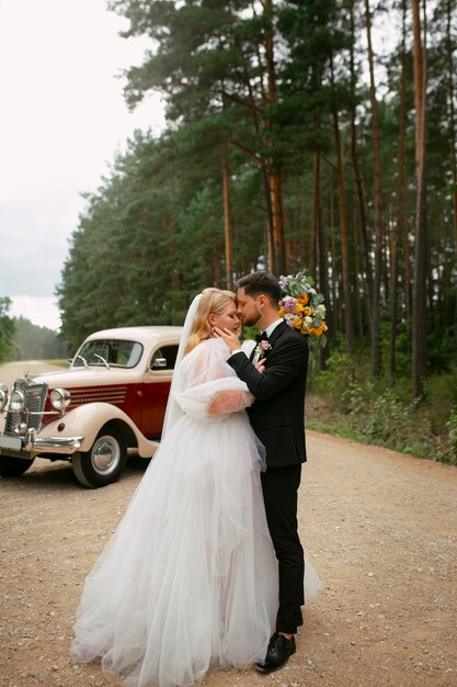 Full shot couple posing with vintage car