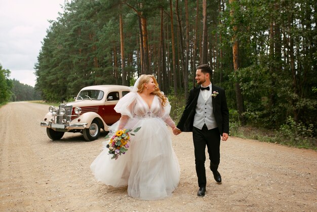 Full shot couple posing with vintage car