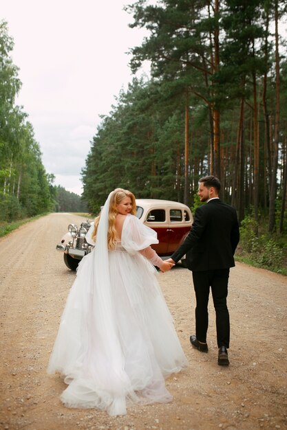 Full shot couple posing with vintage car