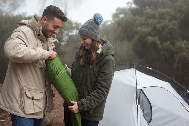 Full shot couple putting up a tent