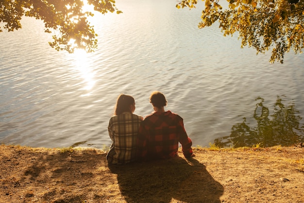 Full shot couple sitting by the lake