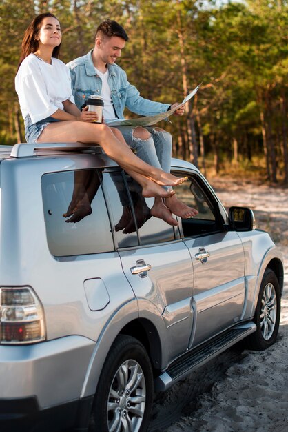 Full shot couple sitting on car