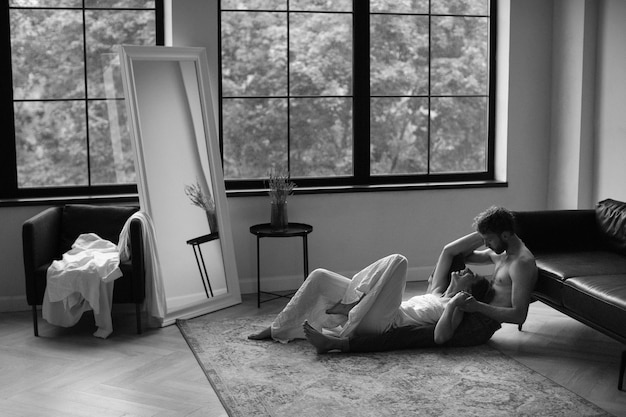 Full shot couple sitting on floor black and white