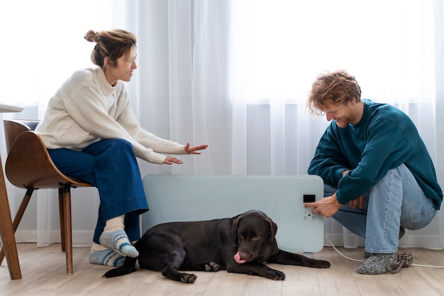 Full shot couple sitting near heater