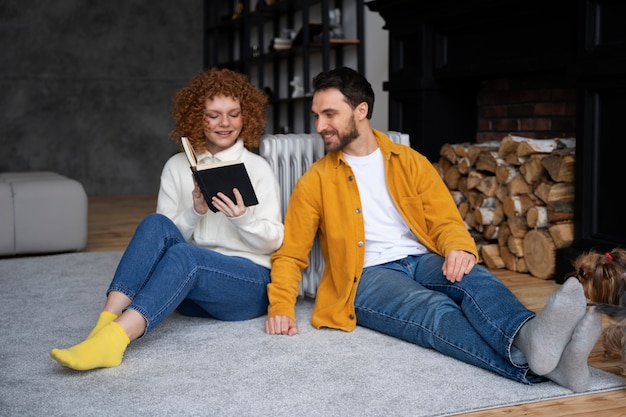 Full shot couple sitting near heater