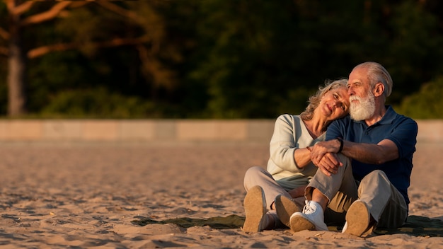 Foto gratuita coppia a tutto campo seduta sulla sabbia