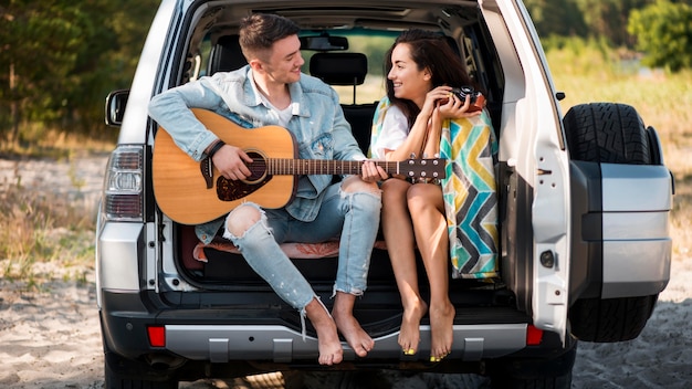 Full shot couple sitting in trunk