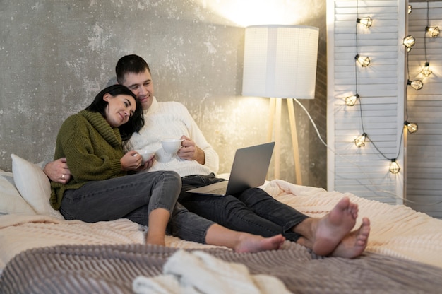 Full shot couple sitting with laptop