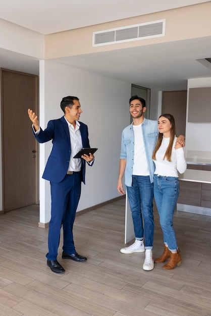Full shot couple talking to real estate agent