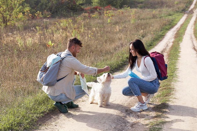 犬と一緒に旅行するフルショットのカップル