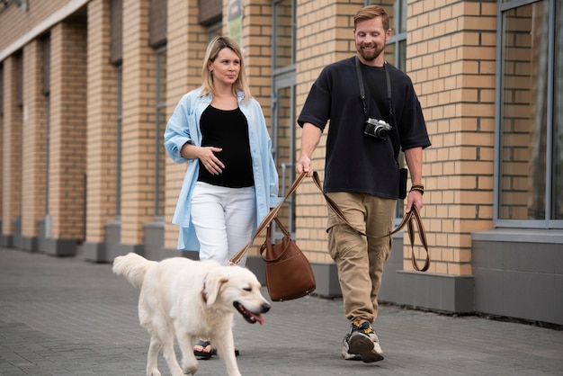 Foto gratuita coppia a tutto campo che cammina con un cane sorridente