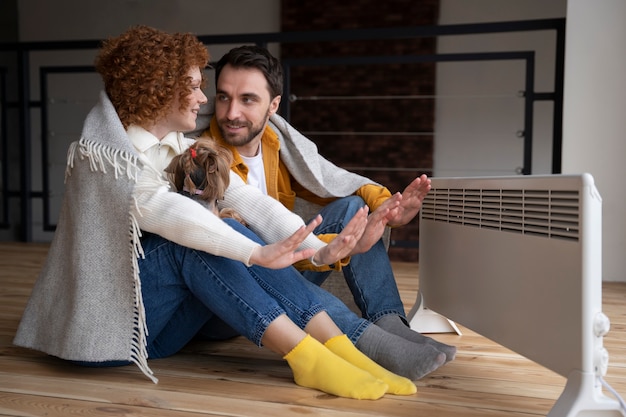 Full shot couple warming up their hands with heater