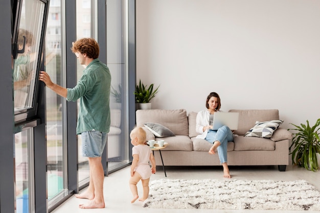 Free photo full shot couple with baby in living room