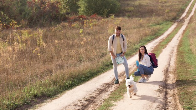 Full shot couple with dog at countryside