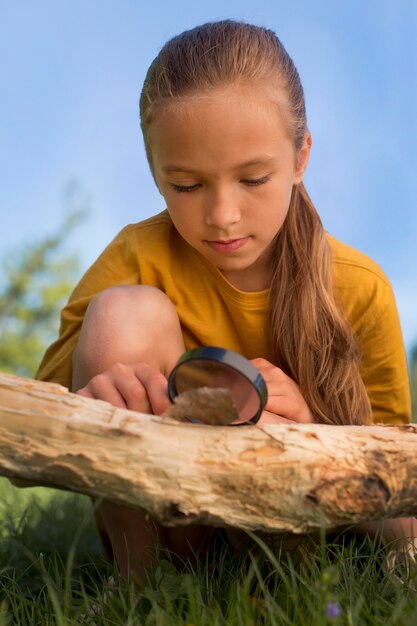 Full shot curious girl observing leaf