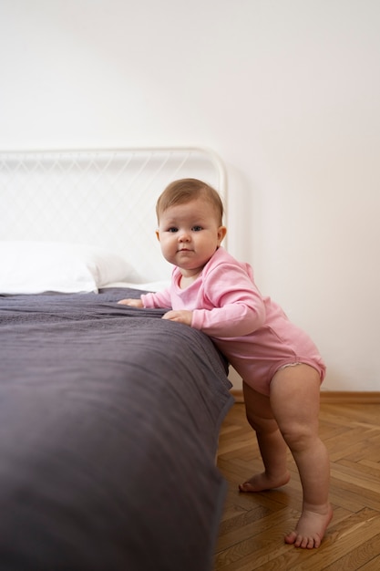 Free photo full shot cute baby leaning on the bed